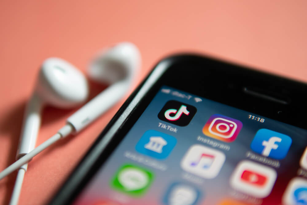 Tampilan icon aplikasi TikTok bersebelahan dengan icon aplikasi Instagram dalam sebuah menu ponsel iPhone